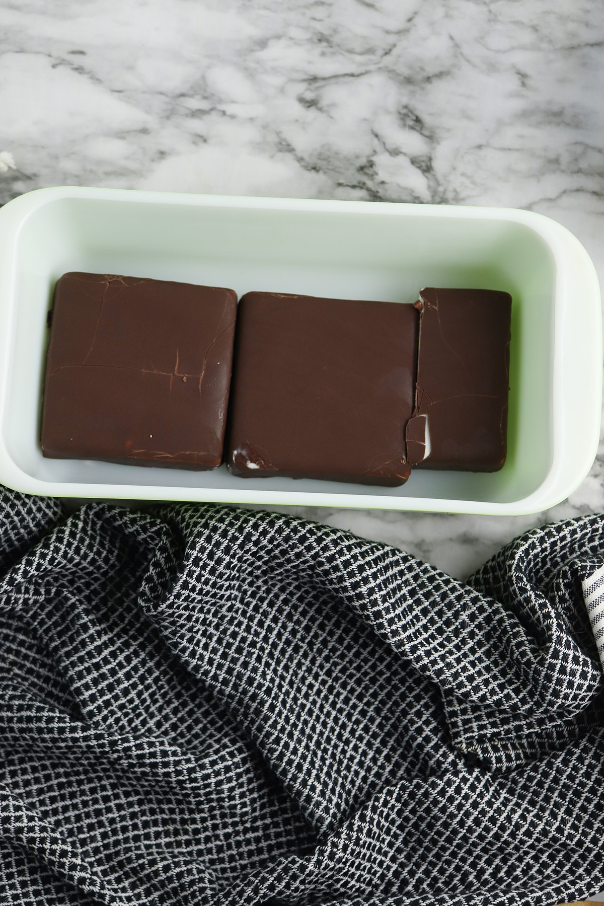 Klondike bars arranged in the bottom of a loaf pan to make the first layer of Klondike ice cream cake.