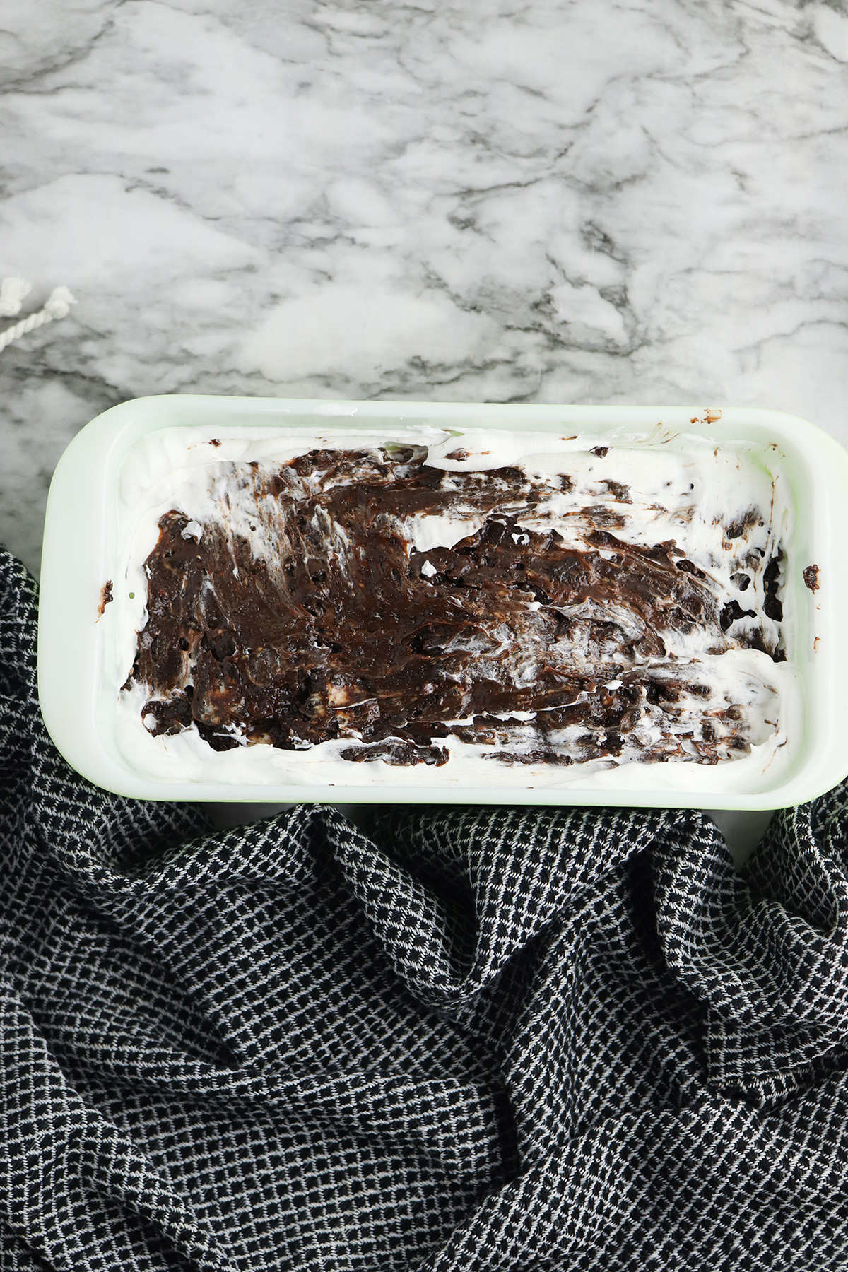 Whipped topping and Oreo hot fudge mixture spread over Klondike bars in a loaf pan.