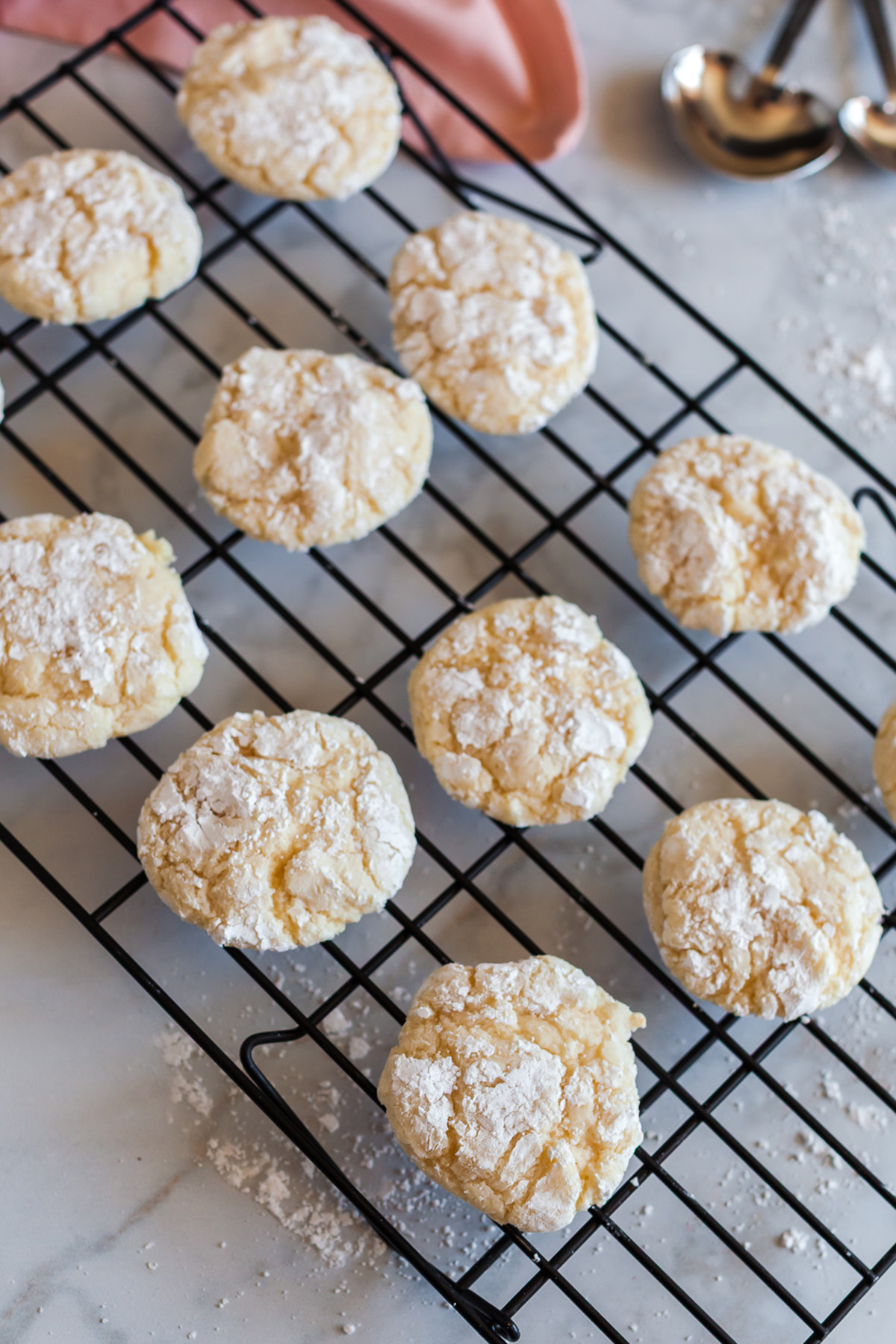 Baked vanilla cake mix crinkle cookies dusted in powdered sugar cooling on a wire rack.