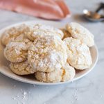 Vanilla cake mix crinkle cookies with a crackled powdered sugar exterior stacked on a serving plate.