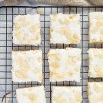 Close overhead of coconut sugar cookie bars with creamy frosting, coconut, and sliced almonds.