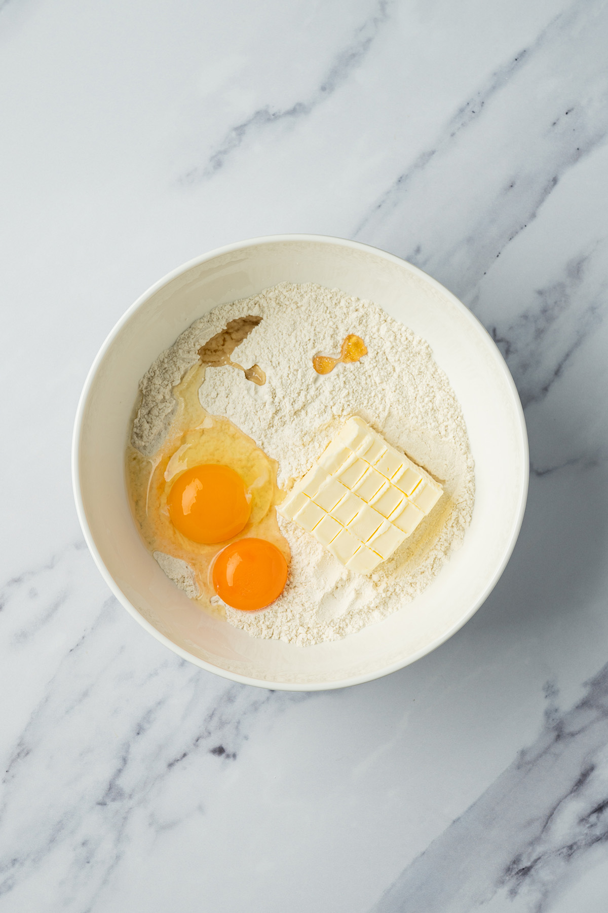 Coconut sugar cookie bar ingredients including butter, eggs, and flour in a bowl before mixing.