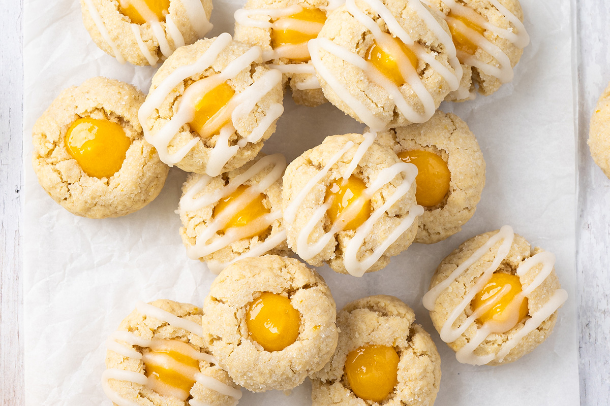 Close-up of lemon curd thumbprint cookies with icing drizzle highlighting the soft centers and crumbly texture.