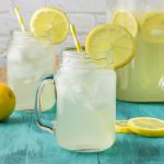 Two mason jars of homemade hard lemonade served over ice with lemon slices