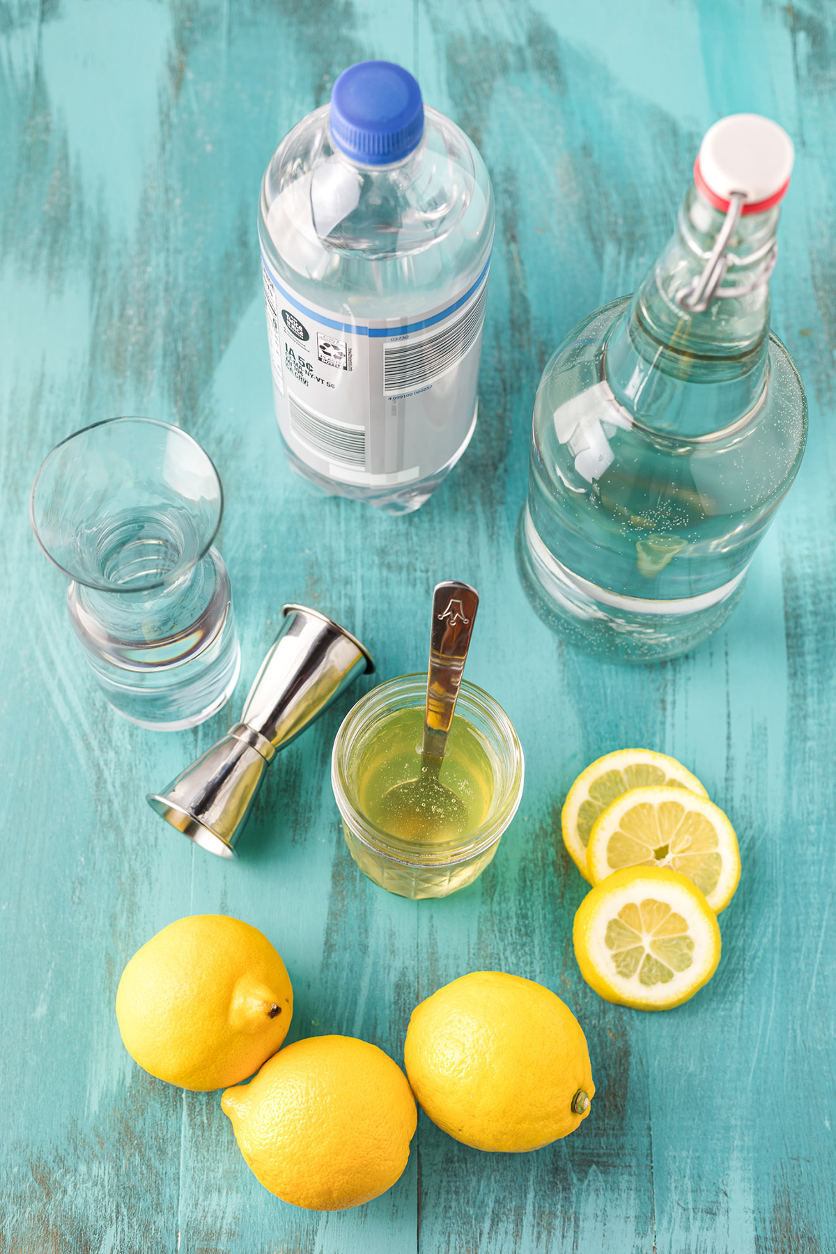 Ingredients for homemade hard lemonade including lemons, vodka, sparkling water and simple syrup.