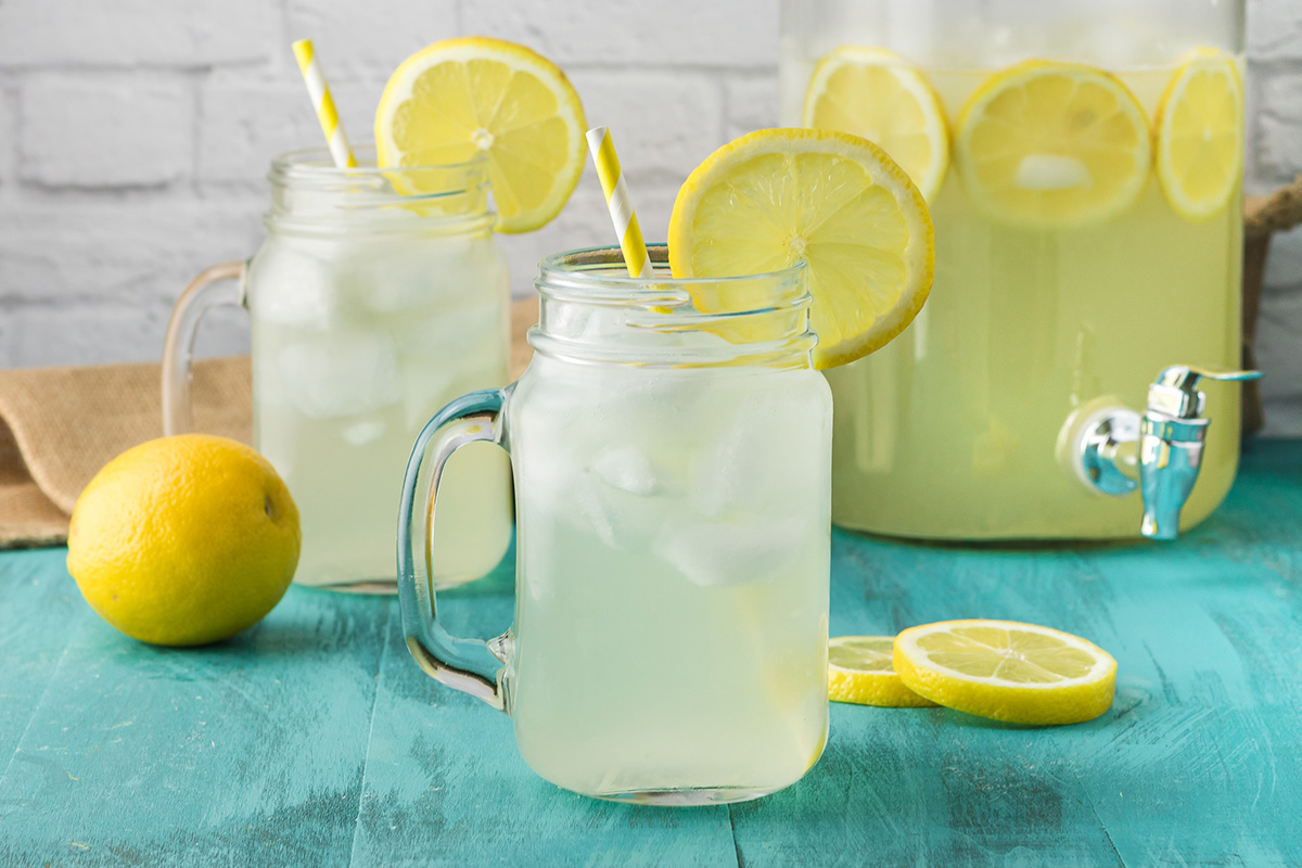 Two mason jars of homemade hard lemonade served over ice with lemon slices