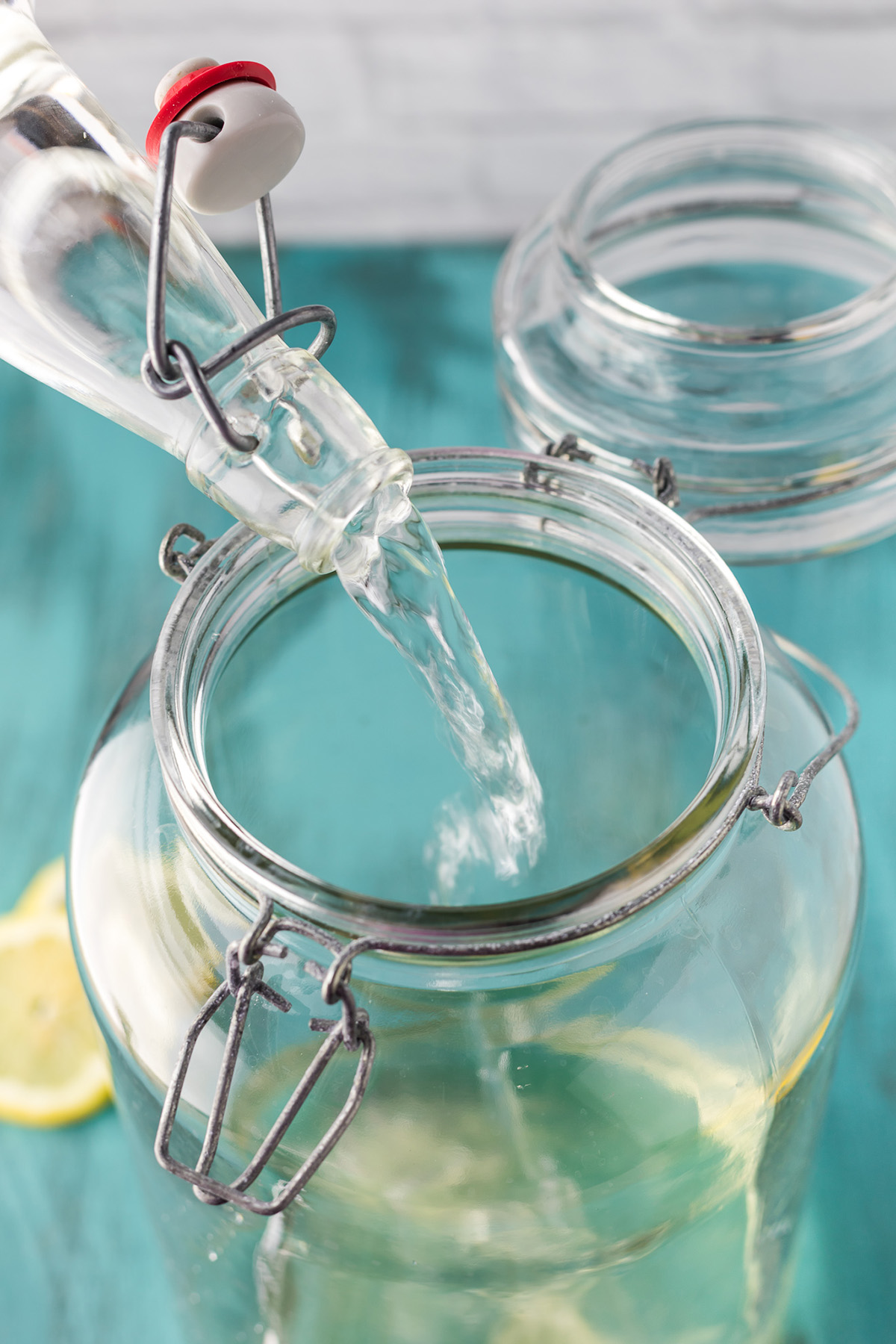 Adding vodka to a glass pitcher for homemade hard lemonade recipe.