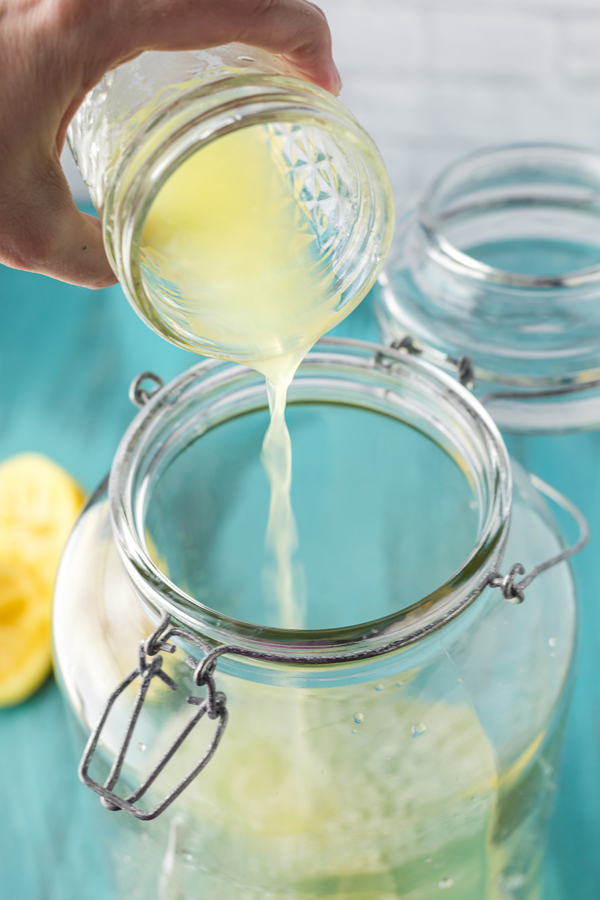 Fresh lemon juice being poured into a jar to make spiked lemonade.