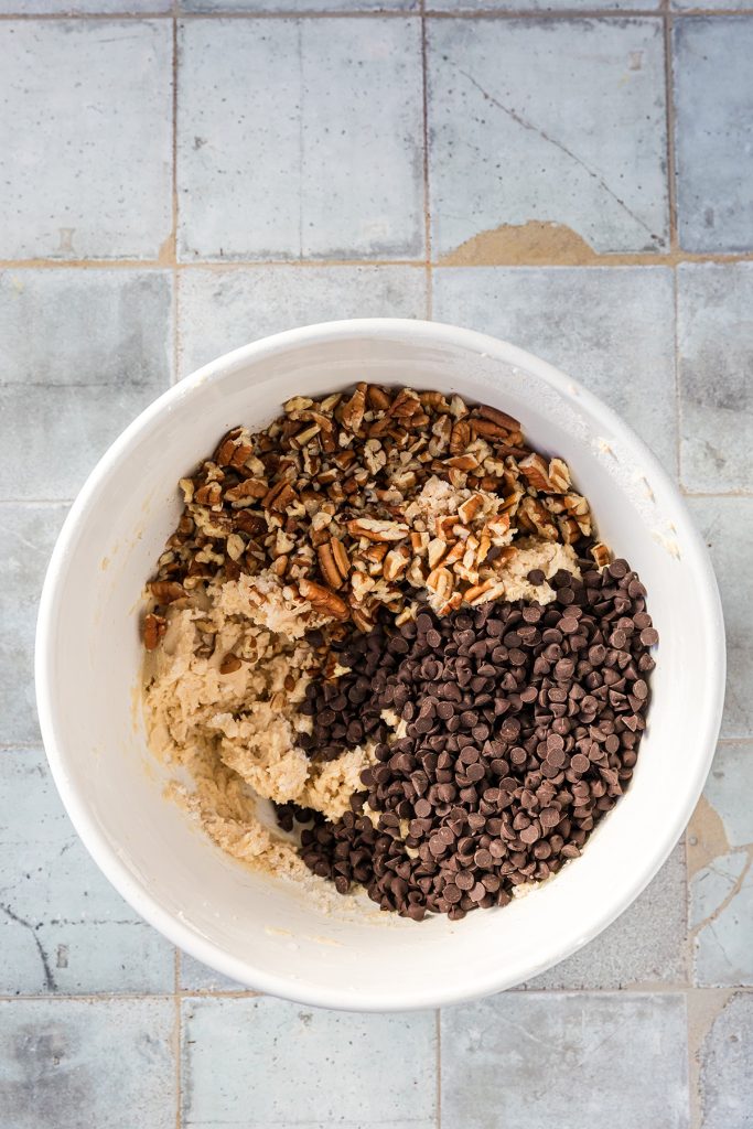 Cookie dough with chopped pecans and mini chocolate chips added for strawberry pecan snowball cookies.
