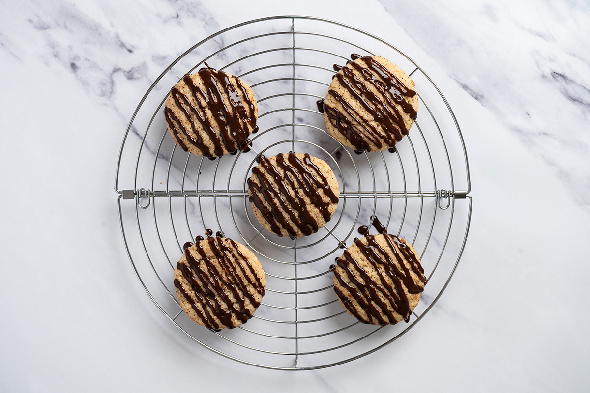 Churro cookies drizzled with chocolate ganache on a round wire rack.