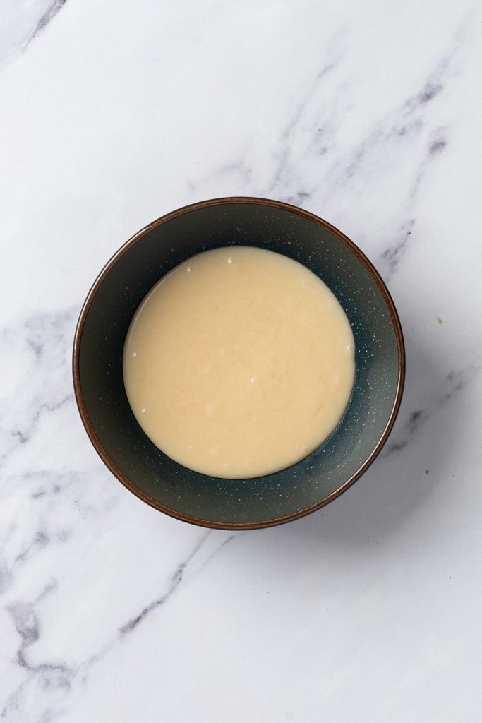 Caramel glaze mixed in a small bowl for drizzling over churro cookies.