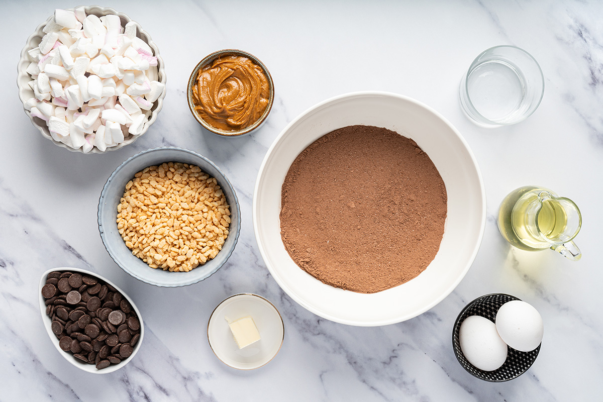 Ingredients for peanut butter crunch bars with brownie mix, marshmallows, chocolate chips, peanut butter and Rice Krispies.