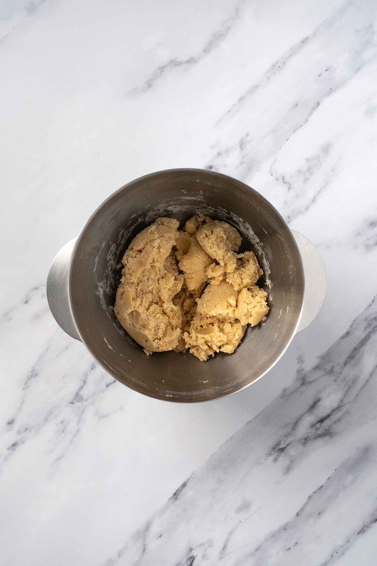 Soft sugar cookie dough mixed in a stand mixer bowl, ready for rainbow sprinkles to be folded in by hand.