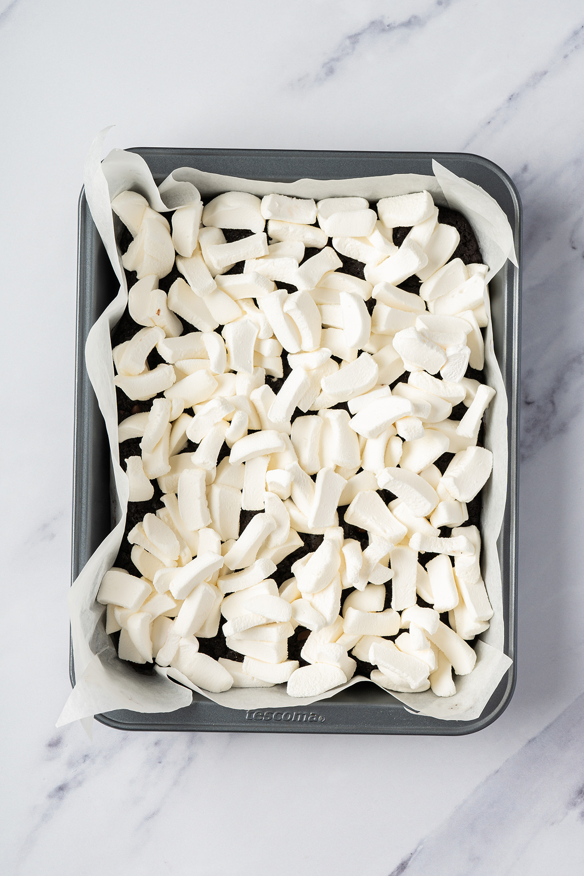 Marshmallows spread over baked brownies for homemade peanut butter crunch bars.