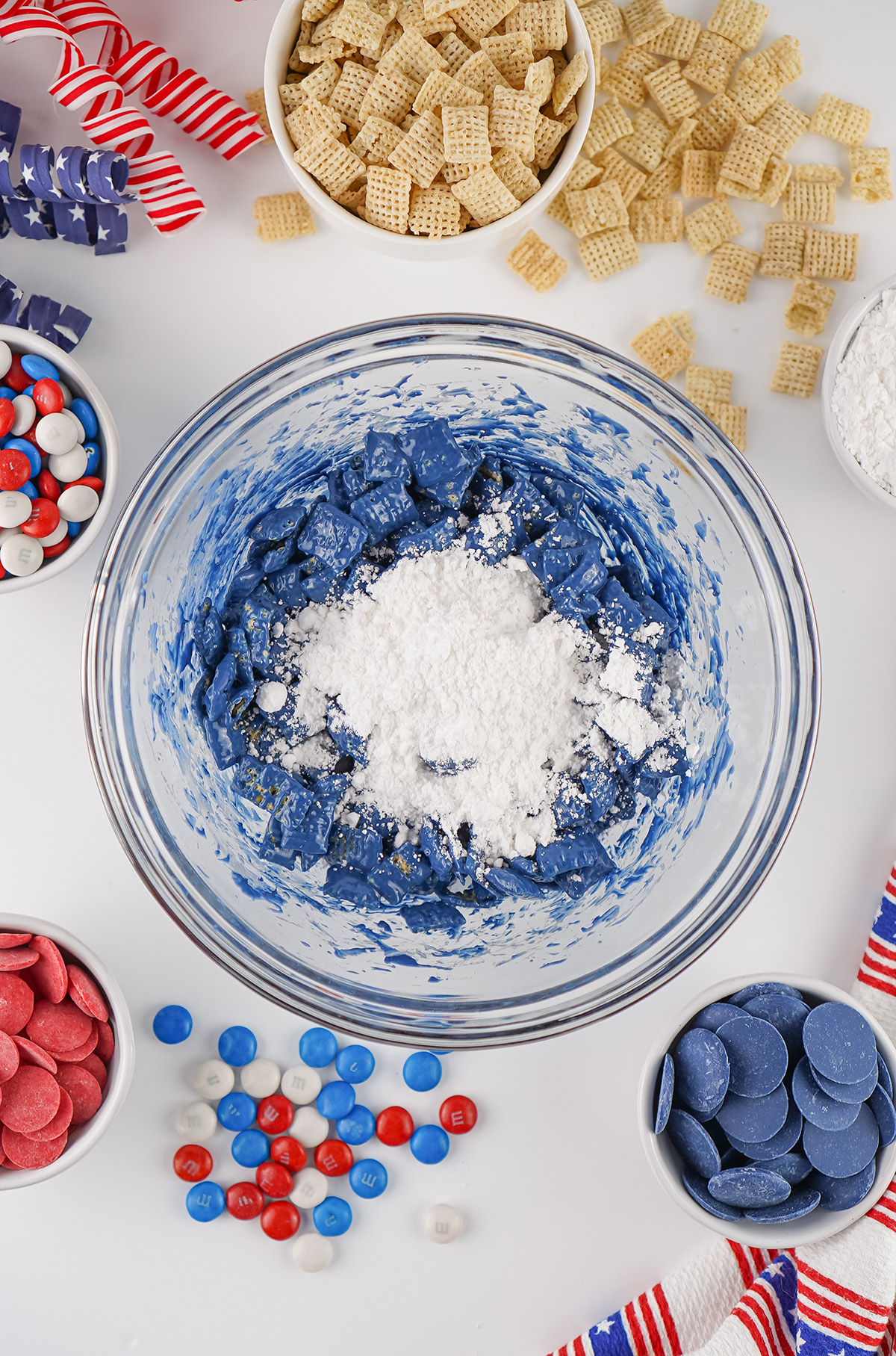 Blue candy coated Chex cereal topped with powdered sugar in a glass bowl.