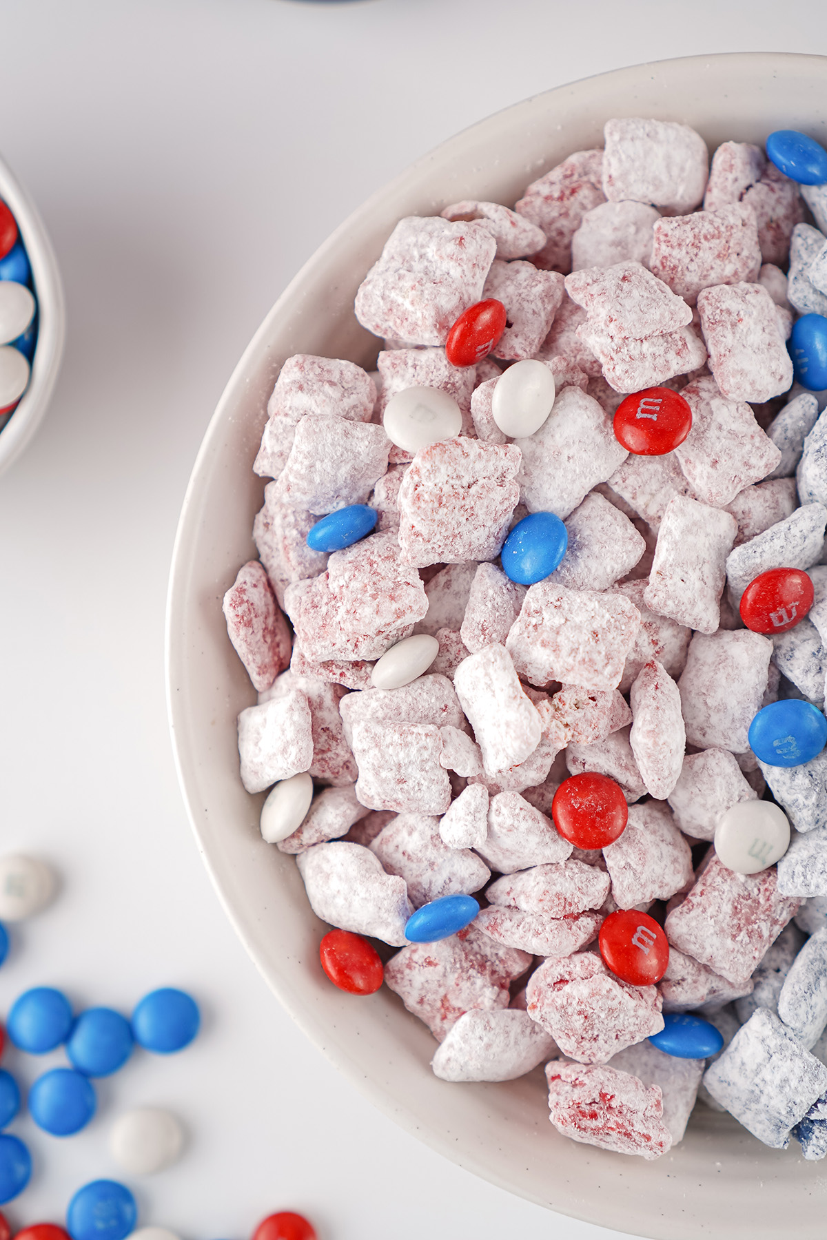 Close up of red white and blue muddy buddies with M&Ms in a white bowl.