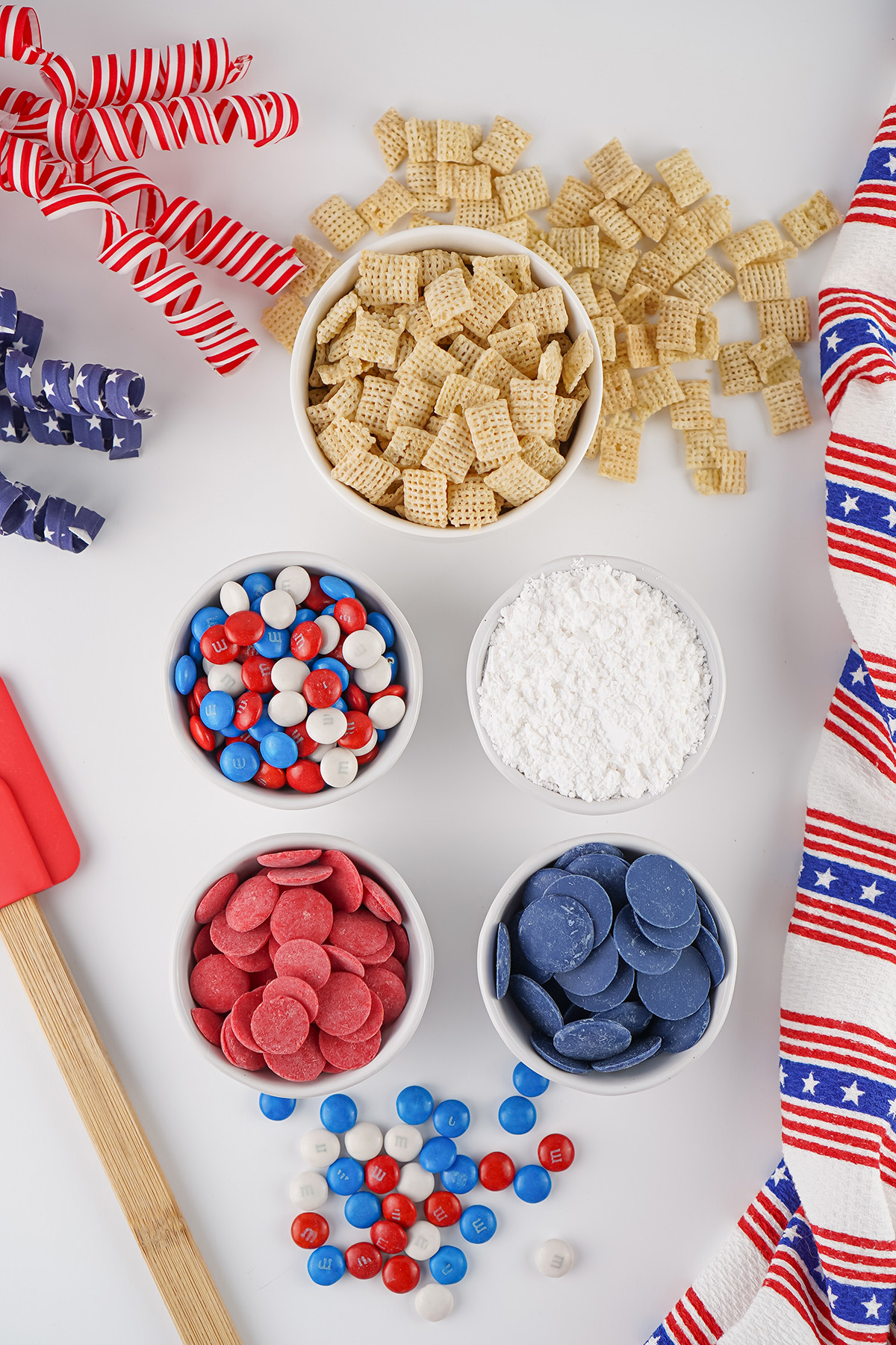 Ingredients for patriotic puppy chow including Chex cereal, powdered sugar, red and blue candy melts and M&Ms.