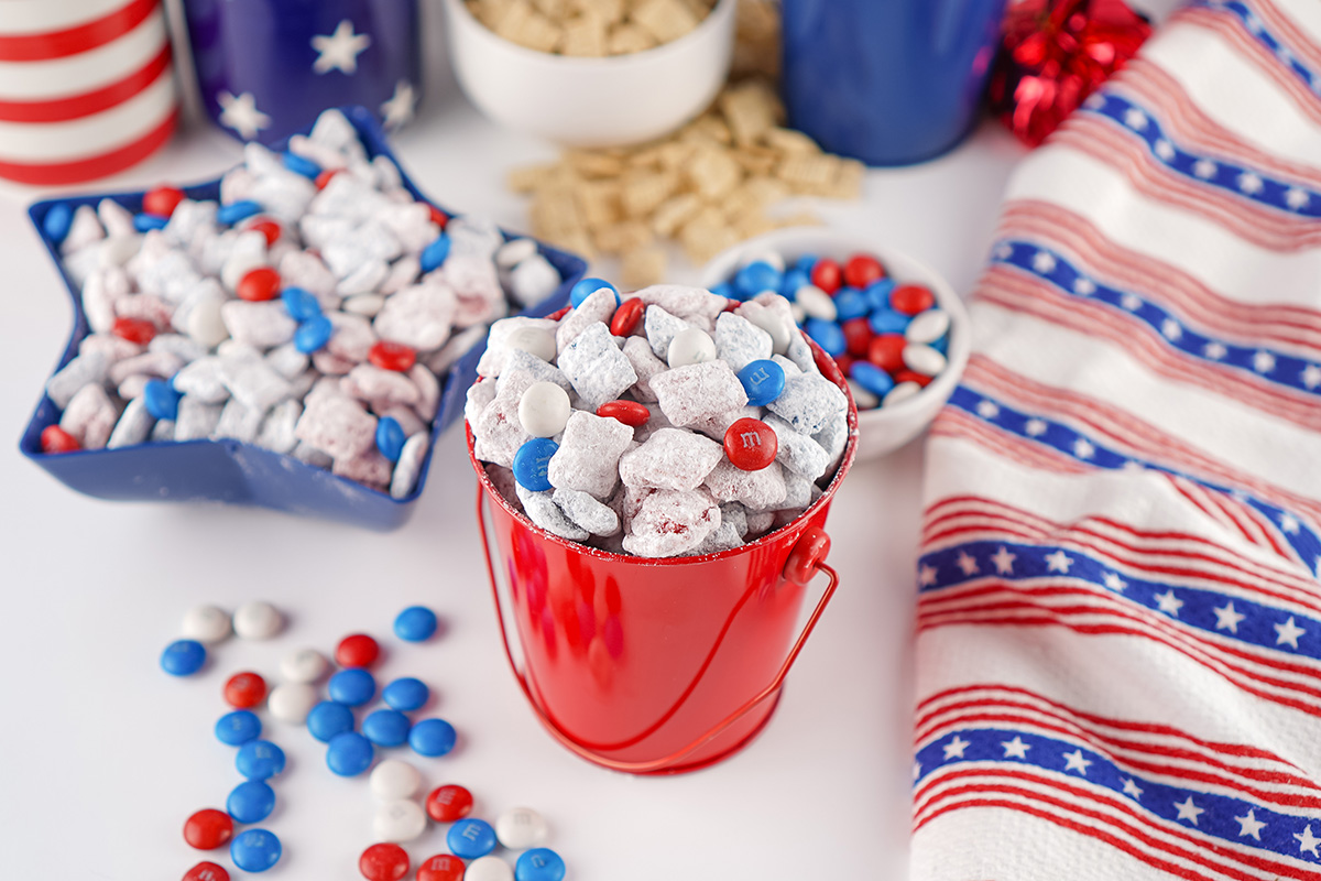 Patriotic puppy chow in a small red bucket and start ceramic dish ready to be served a holiday party.