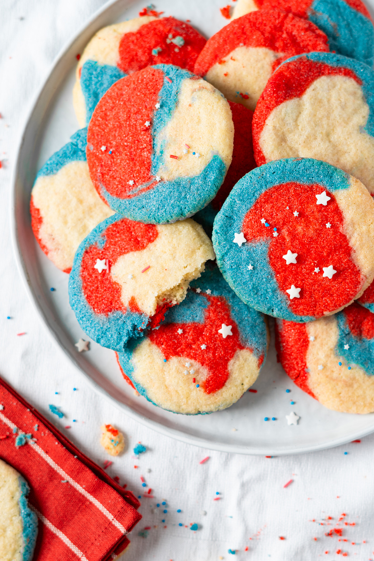 Plate of soft red, white and blue sugar cookies with one cookie bitten.