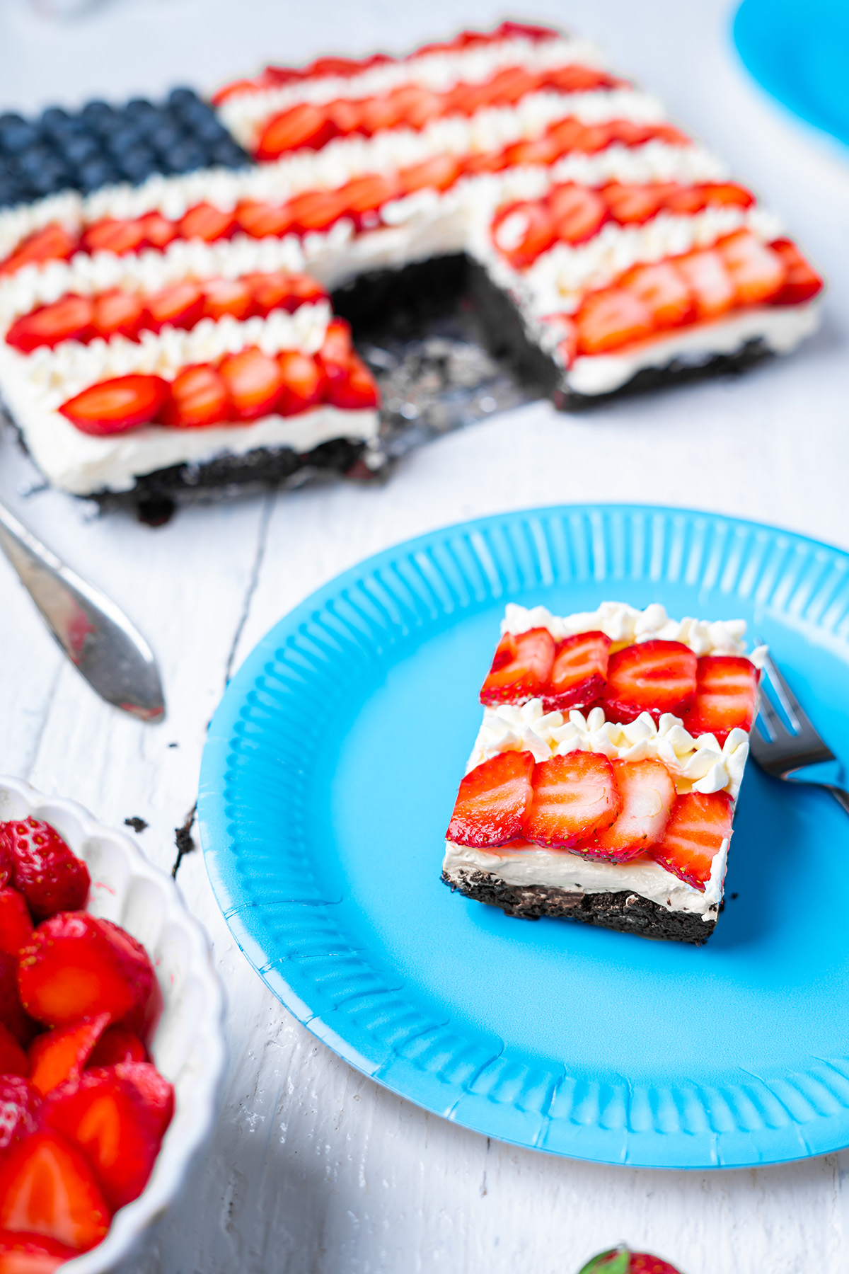 Brownie flag slice served on a blue plate with the decorated brownie pan in the background.