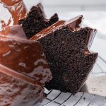 Close-up of a moist chocolate brownie cake slice with glossy ganache dripping over the top.