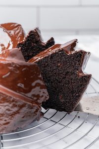 Close-up of a moist chocolate brownie cake slice with glossy ganache dripping over the top.