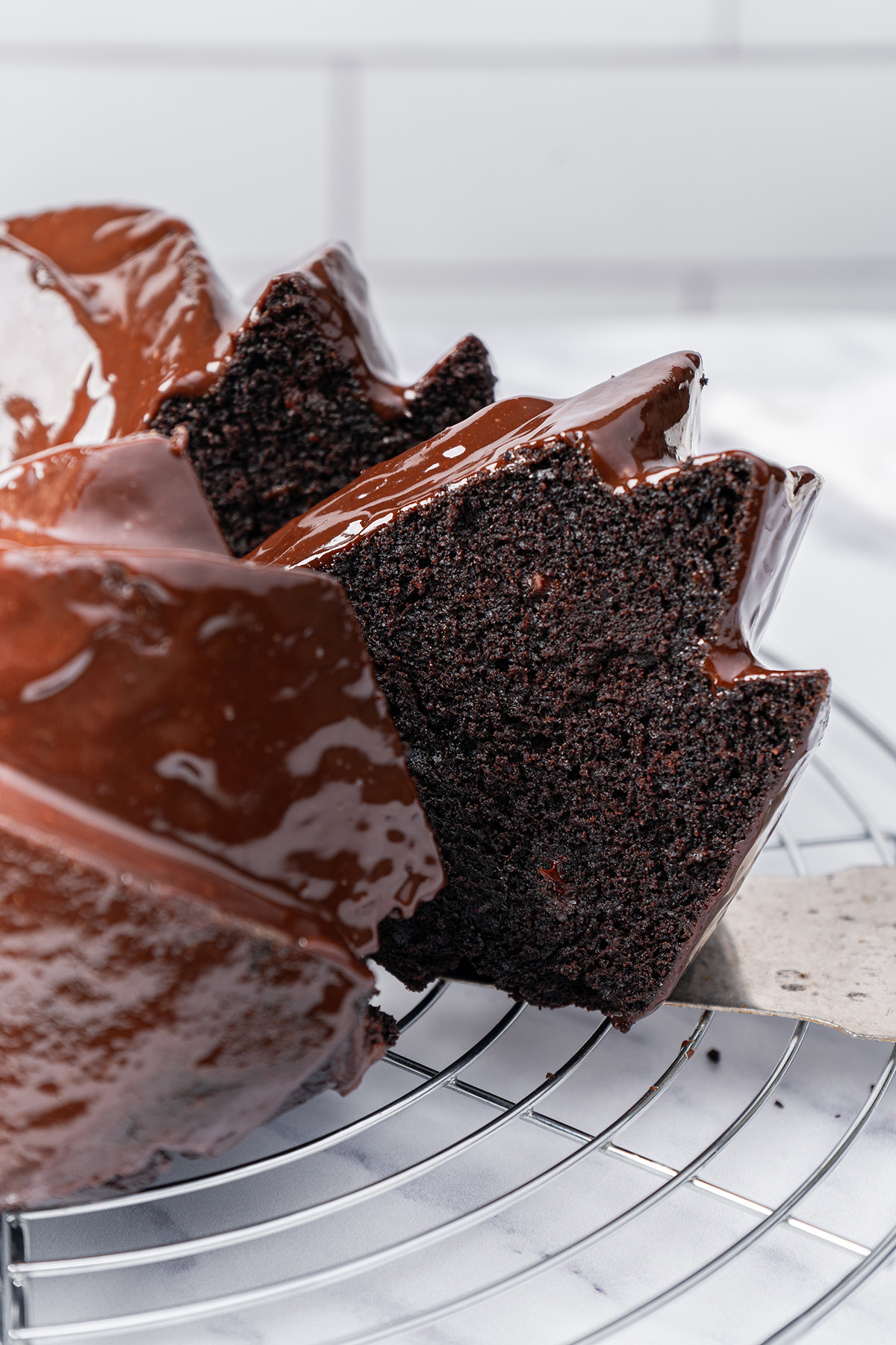 Close-up of a moist chocolate brownie cake slice with glossy ganache dripping over the top.