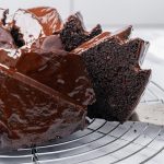 Slice of fudgy chocolate brownie cake being lifted from the Bundt cake with a cake server.