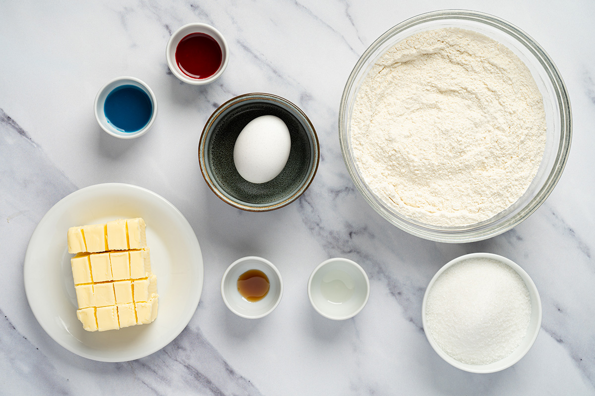 Ingredients for patriotic sugar cookies including cookie mix, butter, egg, extracts and food coloring.