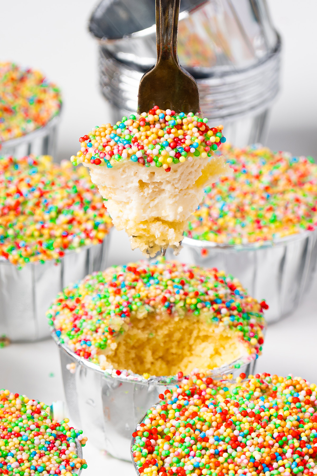Fork lifting a bite of viral dot cake with frosting and crunchy sprinkles.