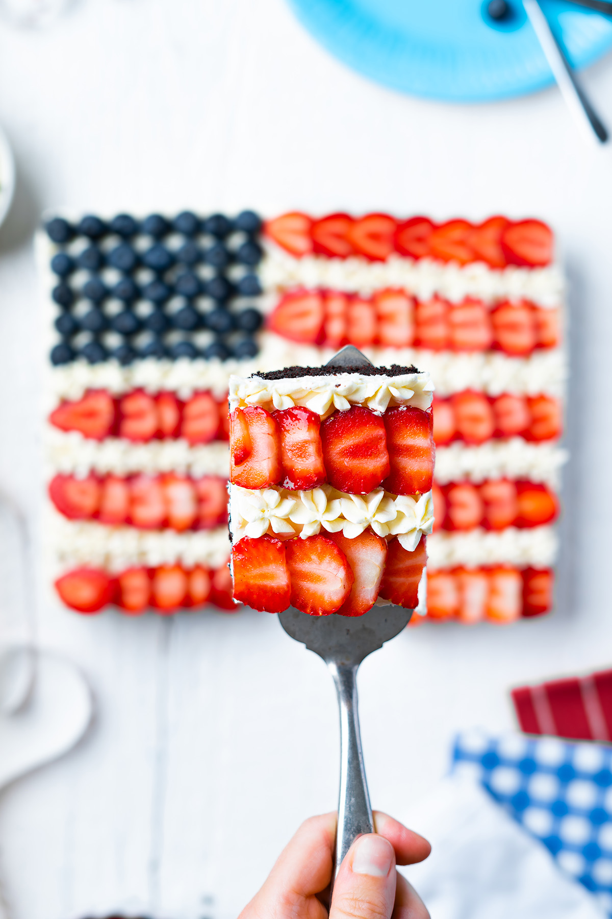 Slice of brownie flag dessert lifted on a spatula with strawberry and frosting stripes.