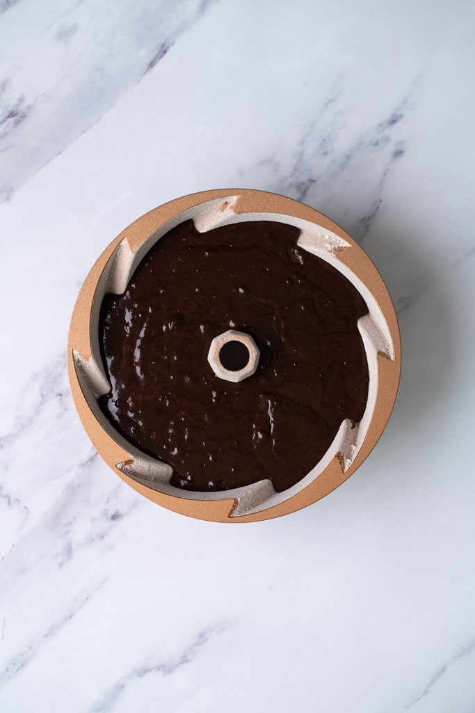 Chocolate brownie cake batter spread into a prepared Bundt pan before baking.