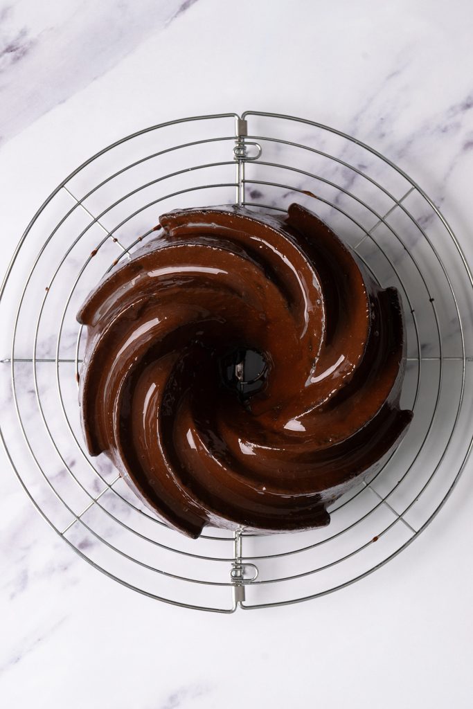 Chocolate brownie Bundt cake covered with shiny ganache on a wire cooling rack.