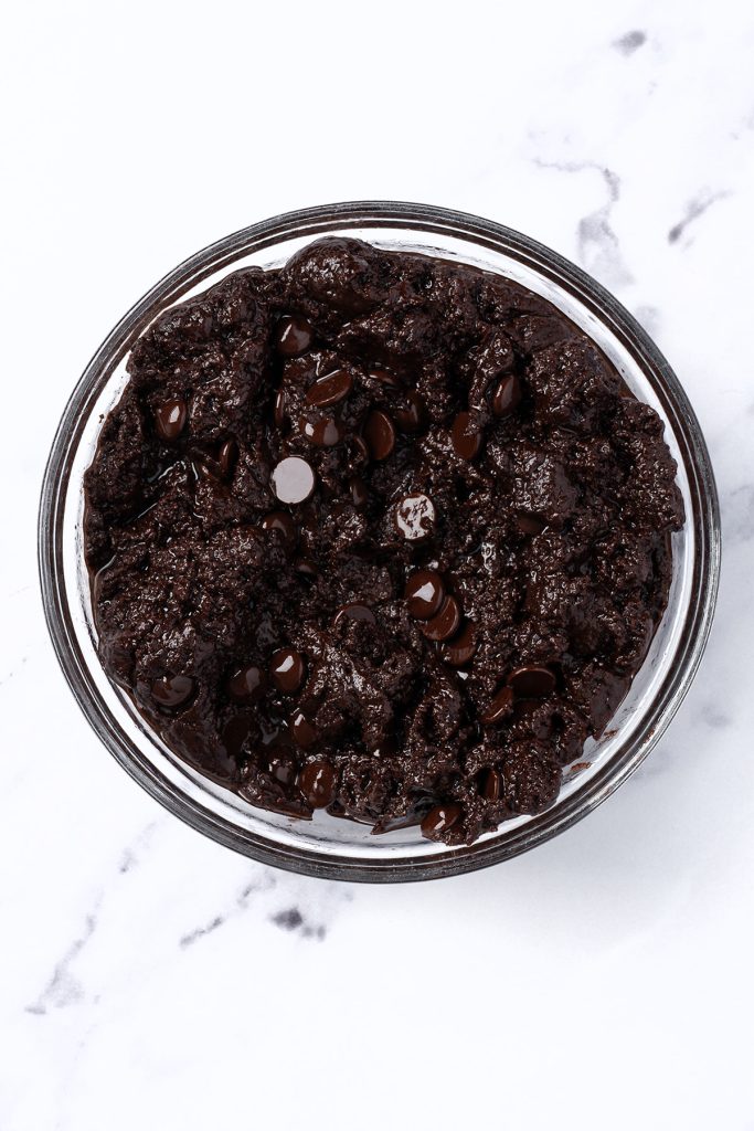 Chocolate brownie batter with chocolate chips in a glass bowl for brownie flag dessert.