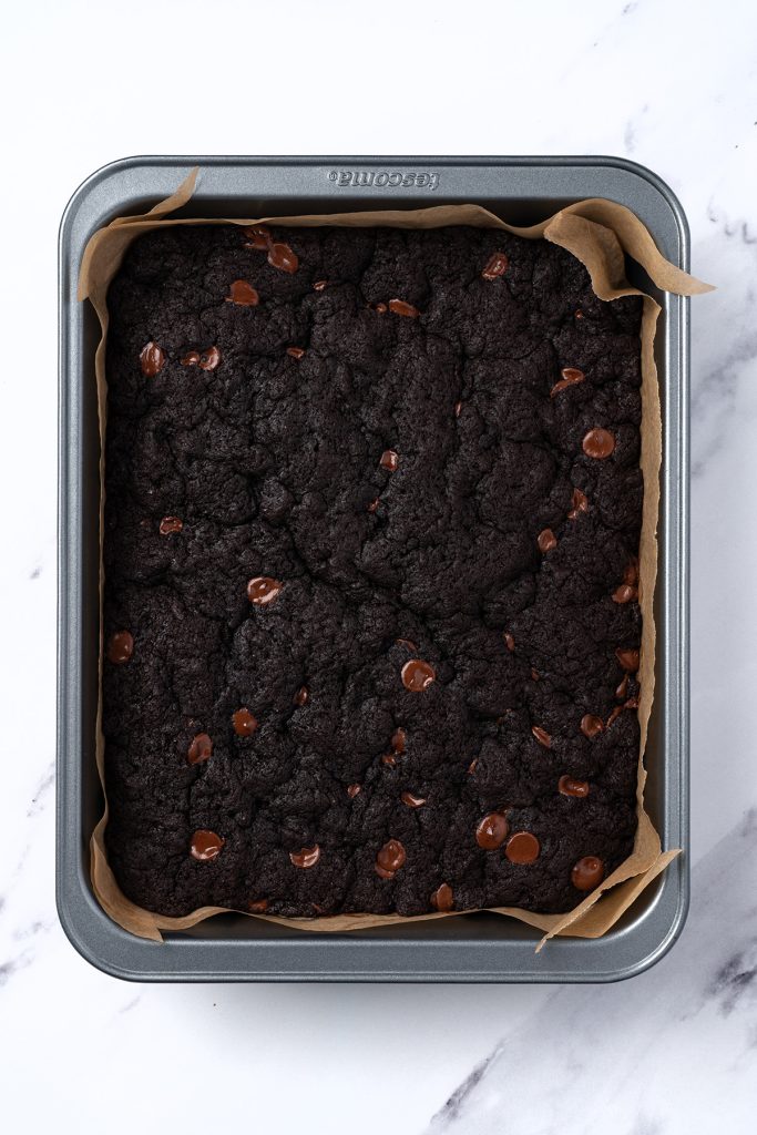Baked chocolate brownies in a parchment lined pan for American flag brownies.