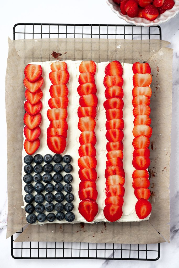 Sliced strawberries arranged in red stripes on frosted flag brownies.