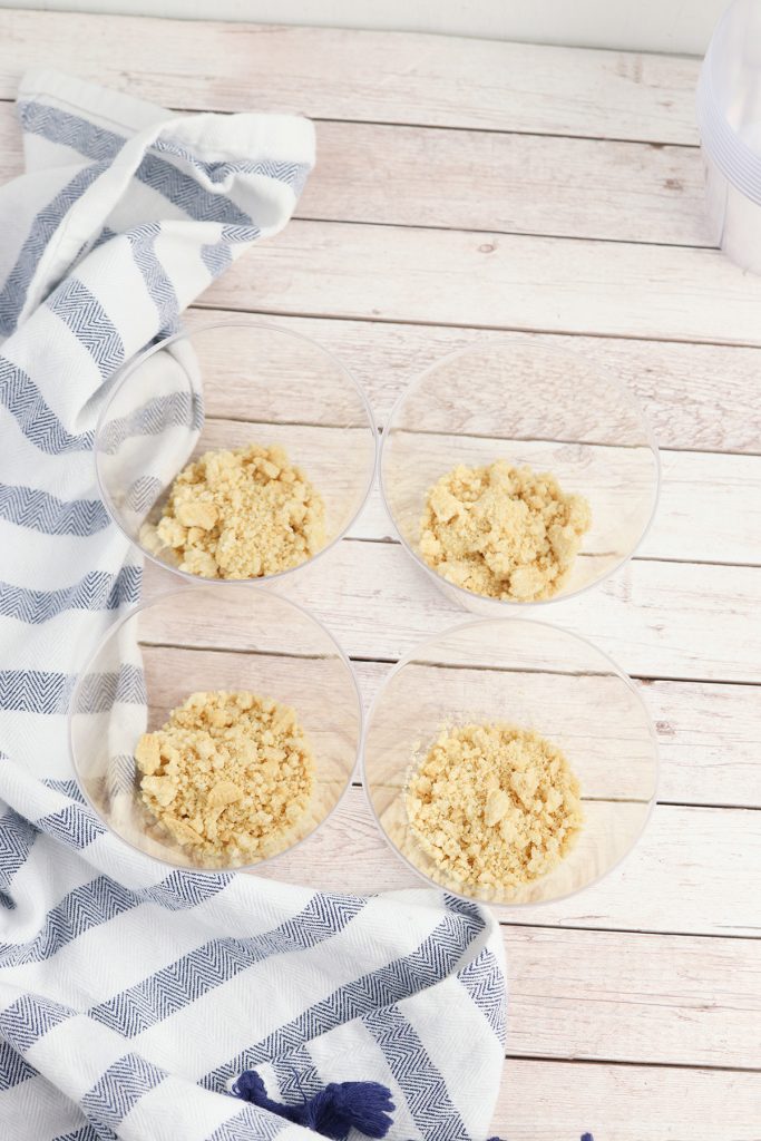Crushed golden Oreo crumbs divided into clear cups for the no bake cheesecake cup base.