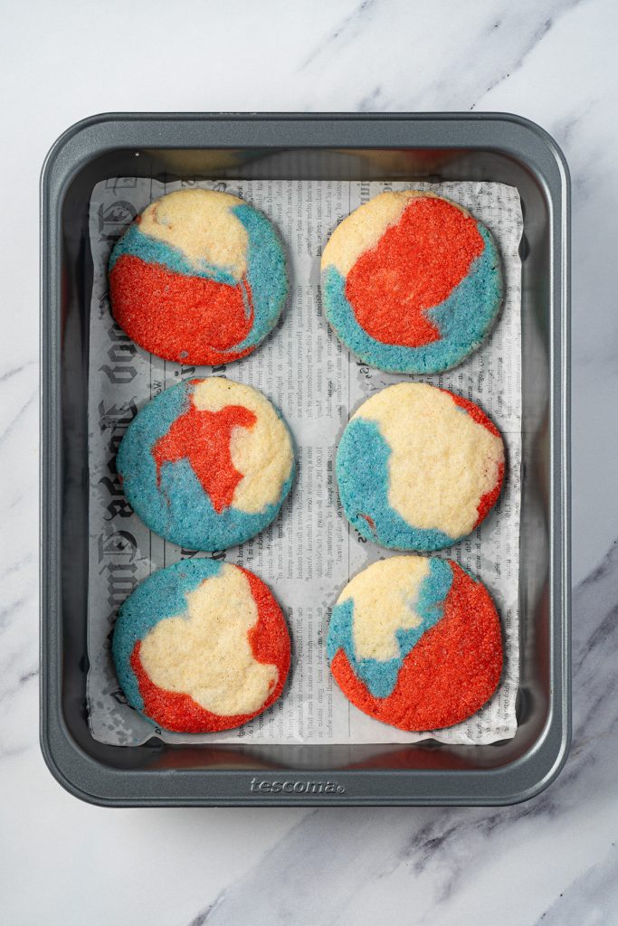 Baked patriotic sugar cookies on a parchment-lined baking pan.