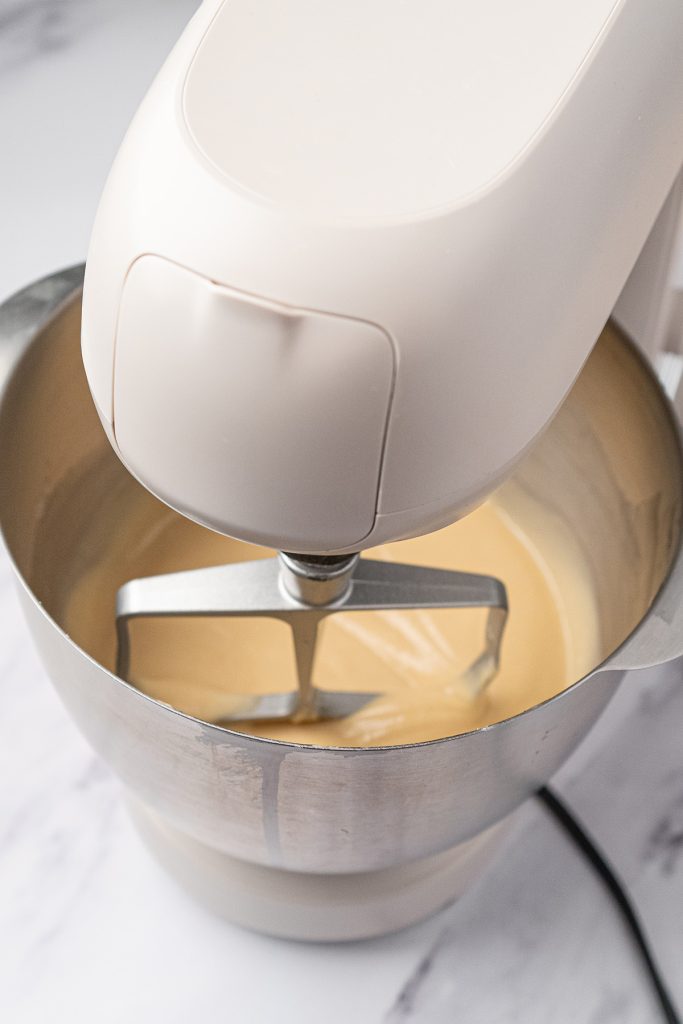 Stand mixer blending vanilla cake batter for mini dot cakes.