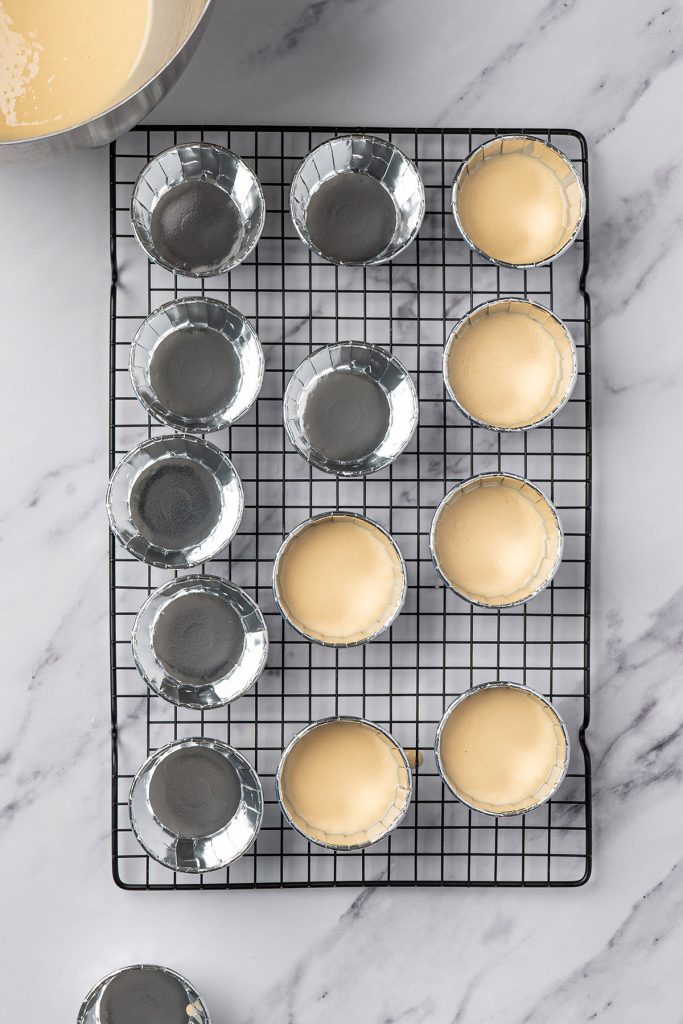 Vanilla cake batter poured into foil ramekins for homemade dot cakes.
