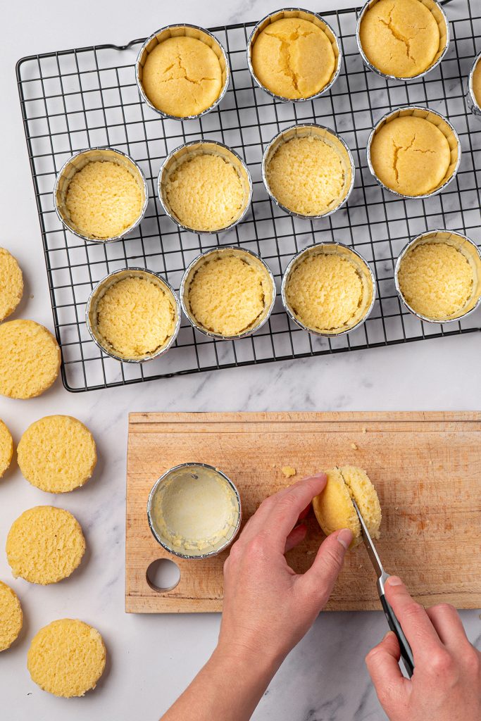 Mini vanilla cakes being sliced in half before filling with frosting.