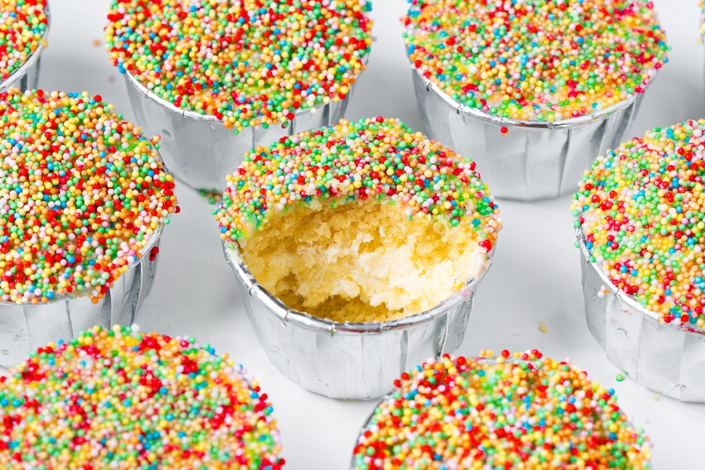 Close-up of a mini dot cake with a bite missing showing the vanilla cake and frosting center.
