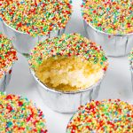 Close-up of a mini dot cake with a bite missing showing the vanilla cake and frosting center.
