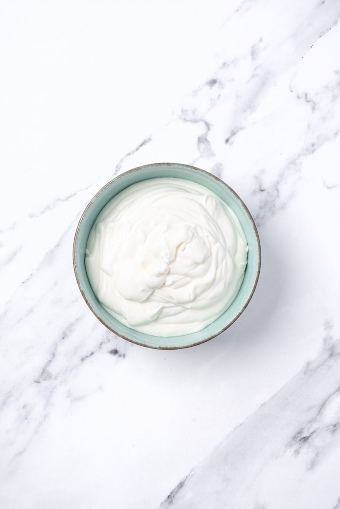 Creamy frosting filling in a bowl for fruit pizza sugar cookie cups.