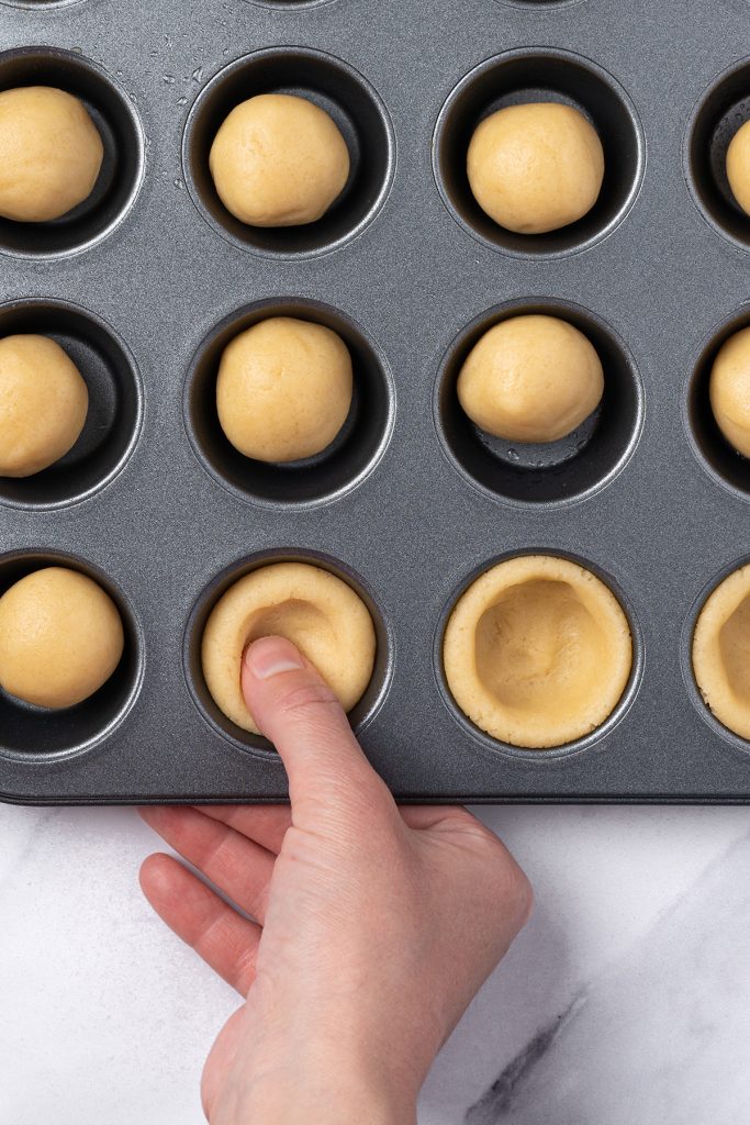Sugar cookie dough pressed into a mini muffin pan to make fruit pizza cookie cups.