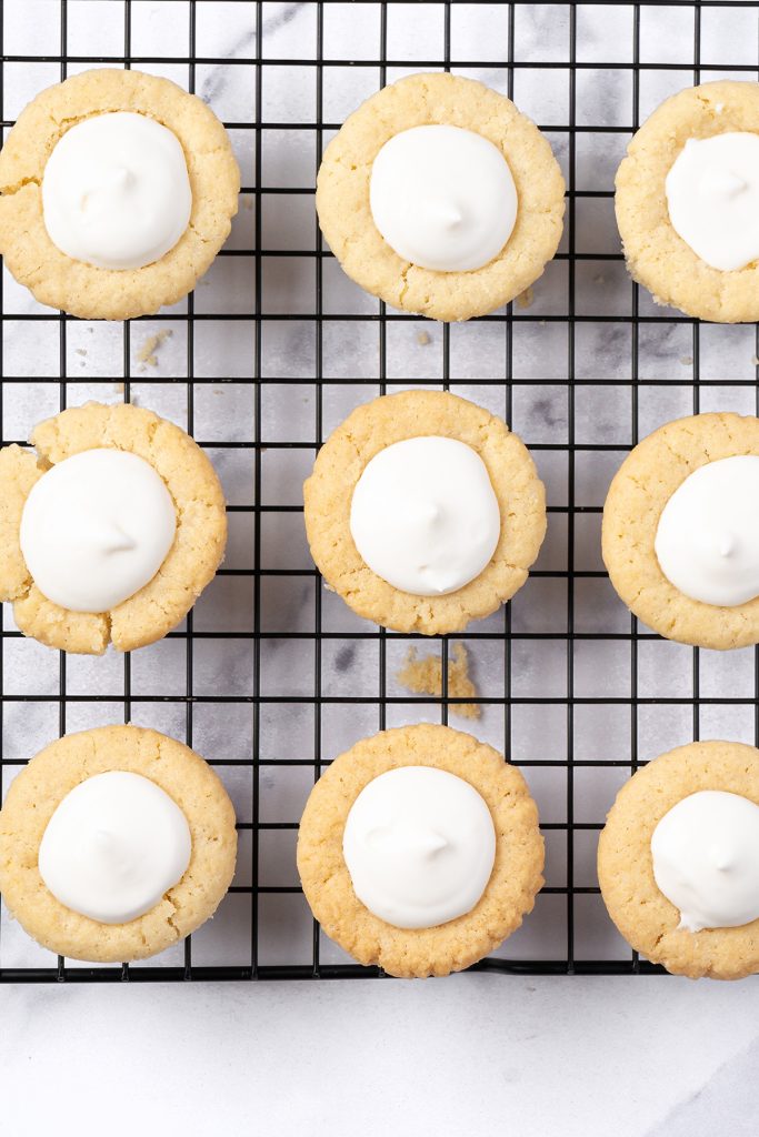 Cream cheese filling being added to mini sugar cookie cups for fruit pizza bites.