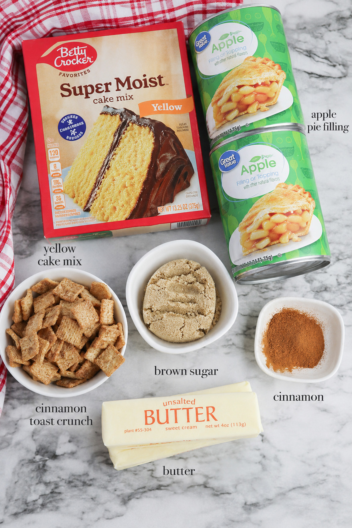 Ingredients for Cinnamon Toast Crunch apple dump cake including yellow cake mix, apple pie filling, cereal, brown sugar, butter, and cinnamon.