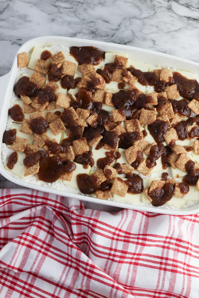 Brown sugar, cinnamon, and melted butter mixture drizzled over Cinnamon Toast Crunch apple dump cake before baking.