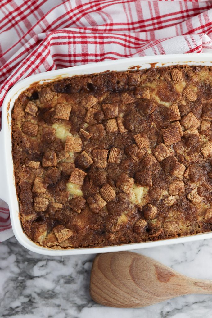 Freshly baked Cinnamon Toast Crunch apple dump cake in a white baking dish with a golden brown cereal topping.